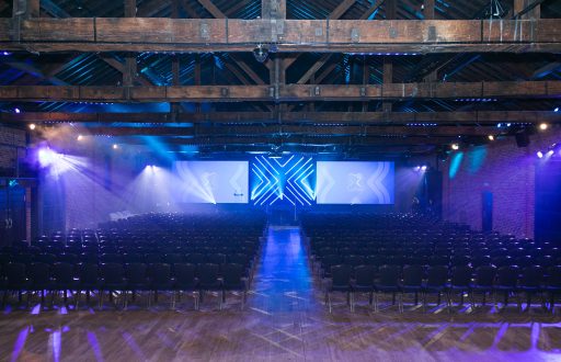 conference space, theatre layout, projector screens, purple and blue spotlights, large event space